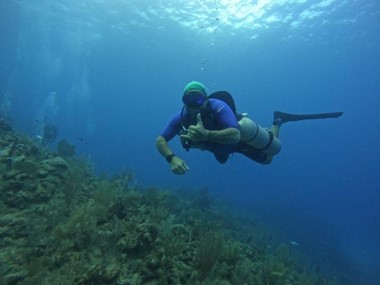 Diver in the open waters of the Pacific Ocean doing a sidemount dive above a coral reef structure off the coast of playa Flamingo, Guanacaste, Costa Rica