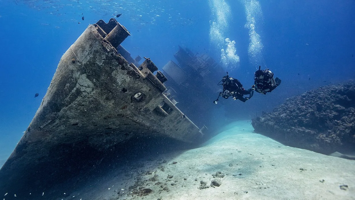 Divers exploring the wreckage of a ship on the ocean floor of the Pacific during a scuba diving Guanacaste wreck dive.