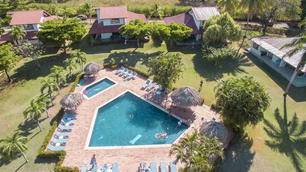 Drone view of Villas Estival on Playa Penca. Homeplate shaped pool surrounded by jungle cabinas right on the beach